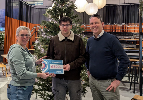 Jongen ontvangt cheque van vertegenwoordiger Driessen Foundation